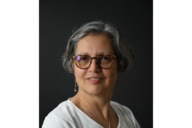 Front-facing profile picture of woman with short grey hair, glasses, and a white shirt