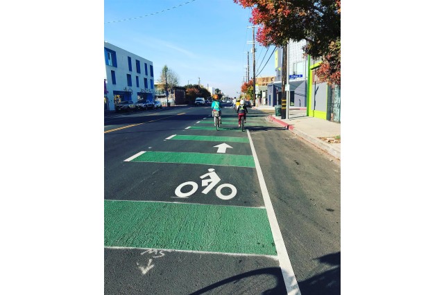 Looking down a white and green-striped bike path with two cyclists further down the street.