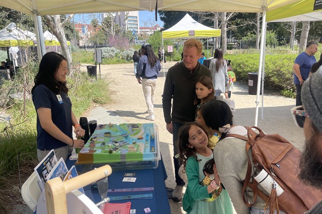 Museum Educators and guests standing on either sides of a table with a 3-D model of buildings and waterways
