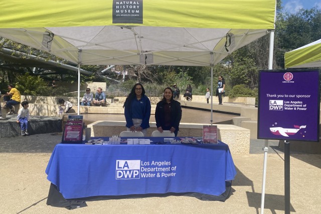 Two LADWP representatives standing behind a table with LADP on it under a yellow tent