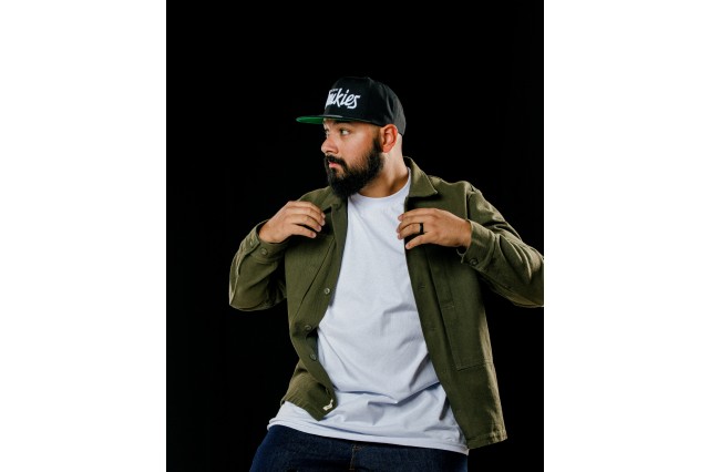 RAMSKILLIT wearing a black baseball cap and holding a green button down open with his hands