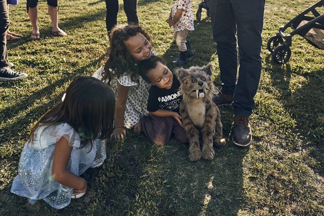 Children hovering around a saber-toothed cat puppet
