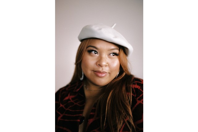 Midi Riperton wearinf a white hat, hoop earrings, and a red and black top