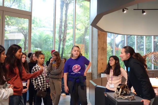Museum Educator leaning over a dire wolf skull and facing a group of students