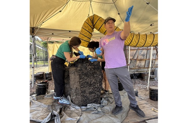 Scientist gesturing with blue gloves and fossils in tar