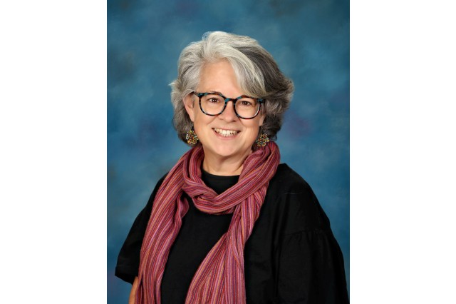 Julie Desmond wearing black glasses and shirt with a pink-red scarf
