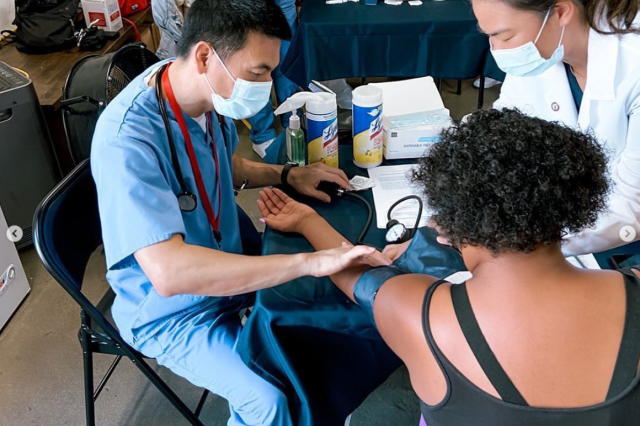 Two medical staff take the vitals of a woman at a free health clinic.