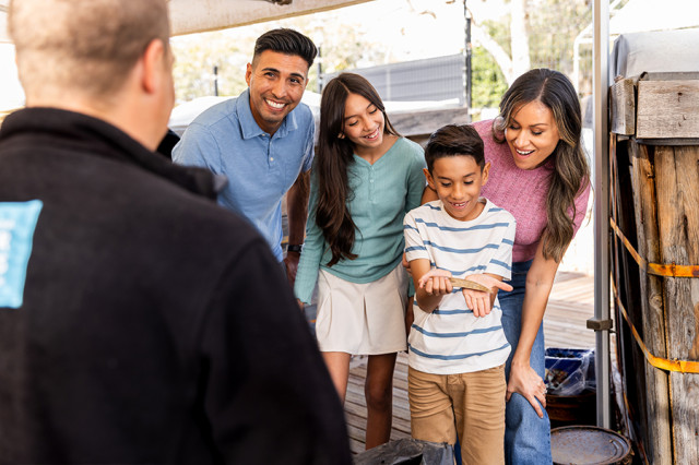 Group of visitors looking over the shoulder of a boy holding a fossil