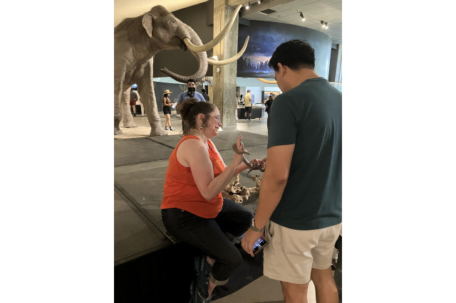 Leslie Gordon holding up a snake towards a visitor