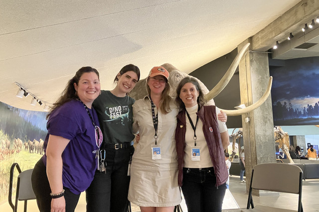 Museum staff standing in a row with arms around each other