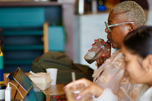 Two customers facing their laptops sip on their coffee while they work.