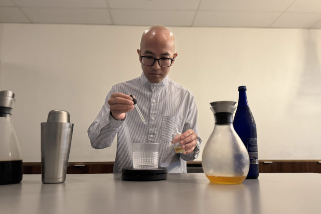 Man using an eye dropper to add ingredients to a specialty cup of coffee.