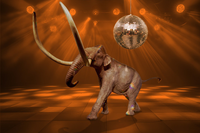 Mammoth sculpture with a disco ball above it, surrounded by orange lighting 