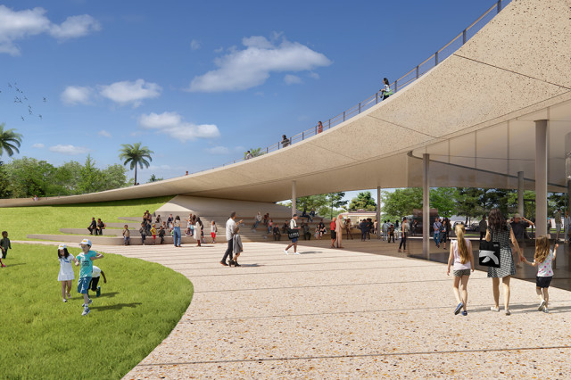 Visitors on a curved, paved walkway, below a roof overhead, through a green lawn