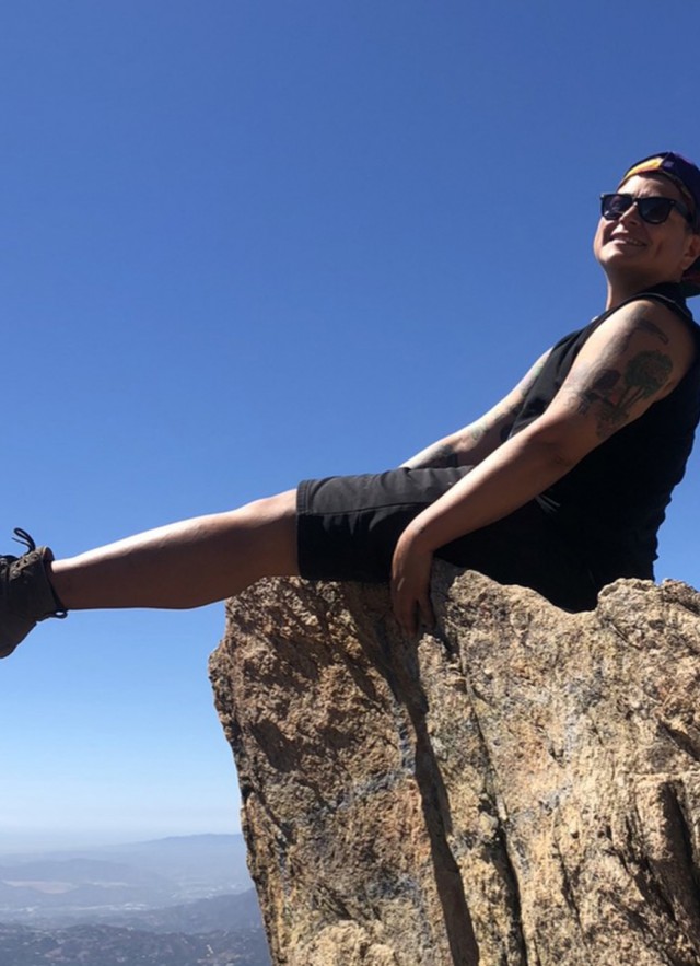 Mari Moreno sitting on a rock in the hills over Los Angeles