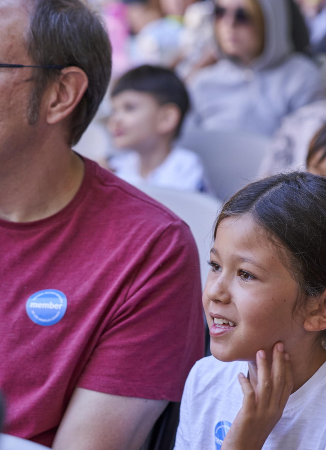Father, daughter, and audience members wearing blue membership stickers
