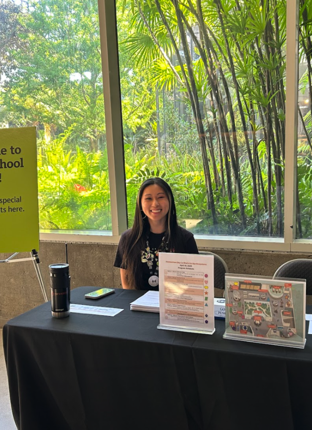 Staff member at Homeschool Day welcome table with signs and maps.