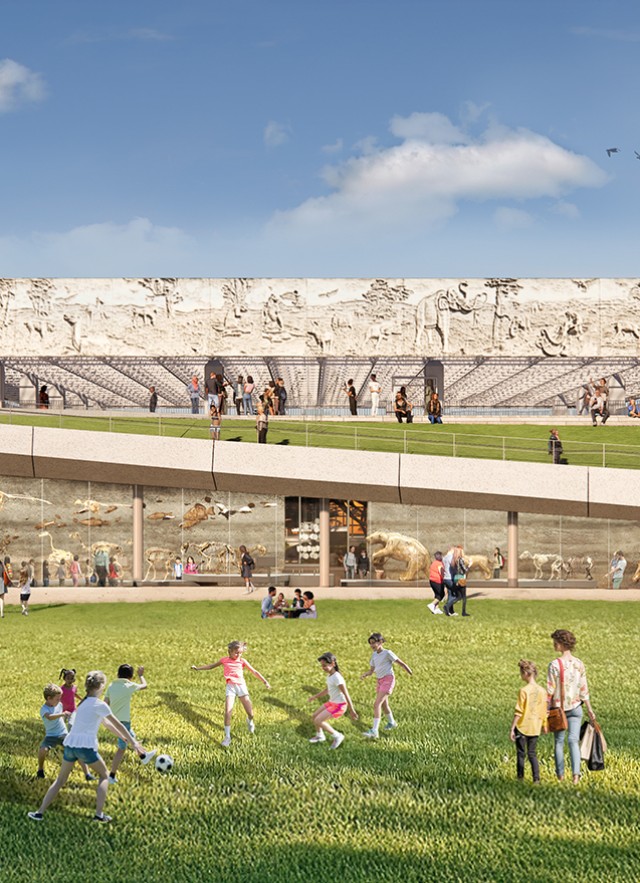 Groups of visitors gathered on a grass lawn in front of a glass wall with skeletons behind it and a ramp in the distance