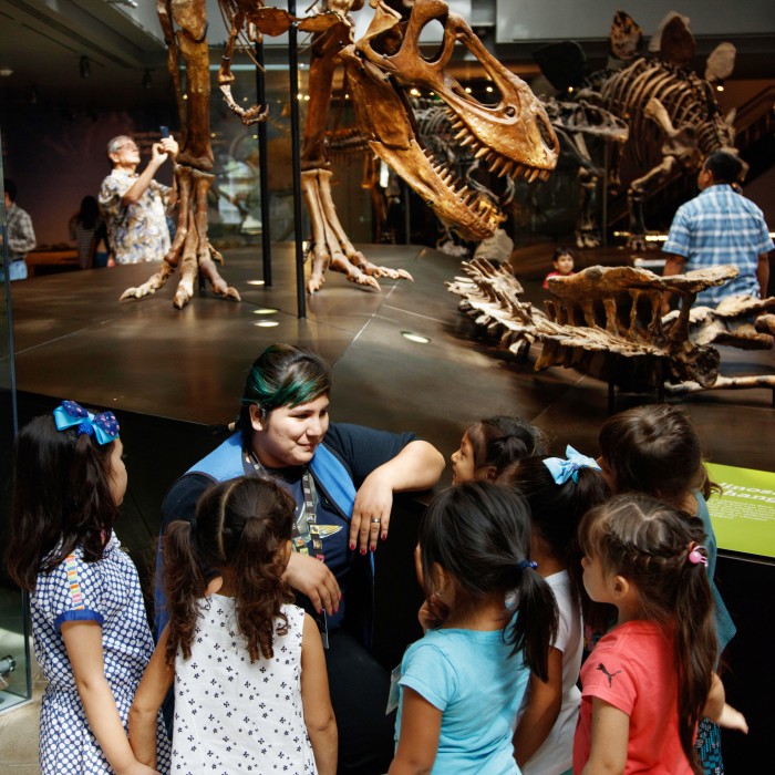 volunteer with kids in dinosaur hall NHM