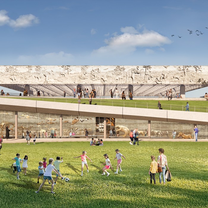 Groups of visitors gathered on a grass lawn in front of a glass wall with skeletons behind it and a ramp in the distance