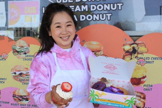 Woman in pink sweater holding donut and donut box