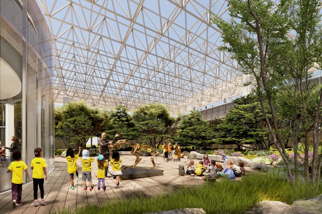 Children in yellow shirts facing a Museum Educator gesturing towards a saber-toothed cat skeleton in an outside courtyard