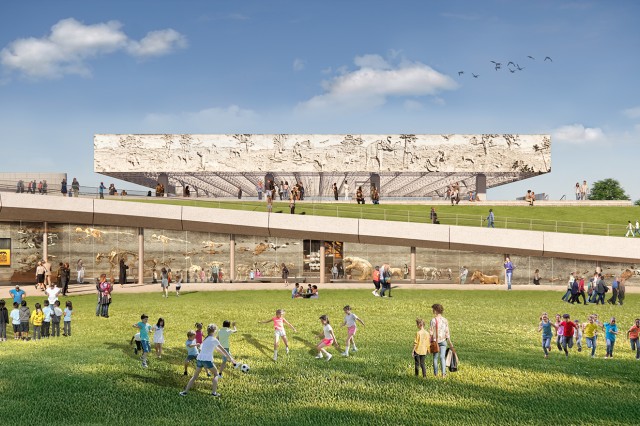 Groups of visitors gathered on a grass lawn in front of a glass wall with skeletons behind it and a ramp in the distance