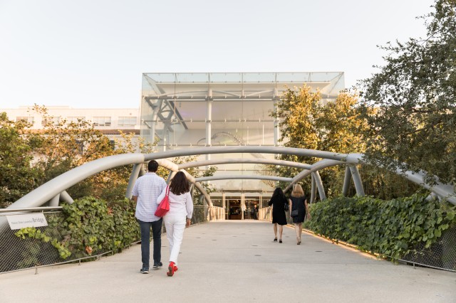 People walking across the Otis Booth Pavilion bridge