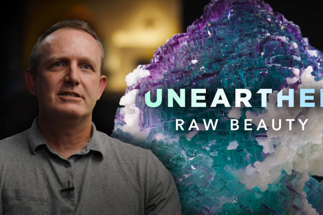 Aaron Celestian in front of a purple, blue, and white crystal mineral specimen