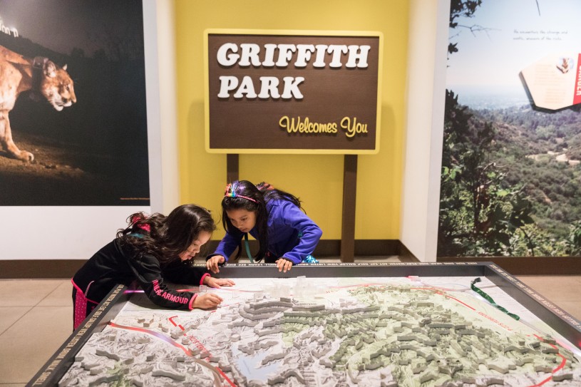 Two girls near Griffith Park sign looking at map in P-22 exhibition