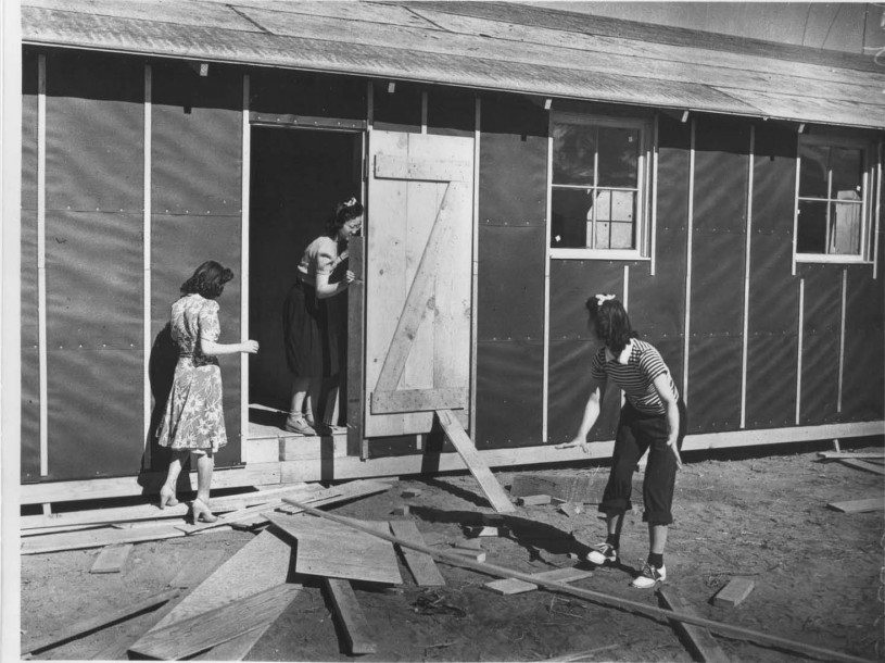 Manzanar - women with lumber in front of a tar papered cabin